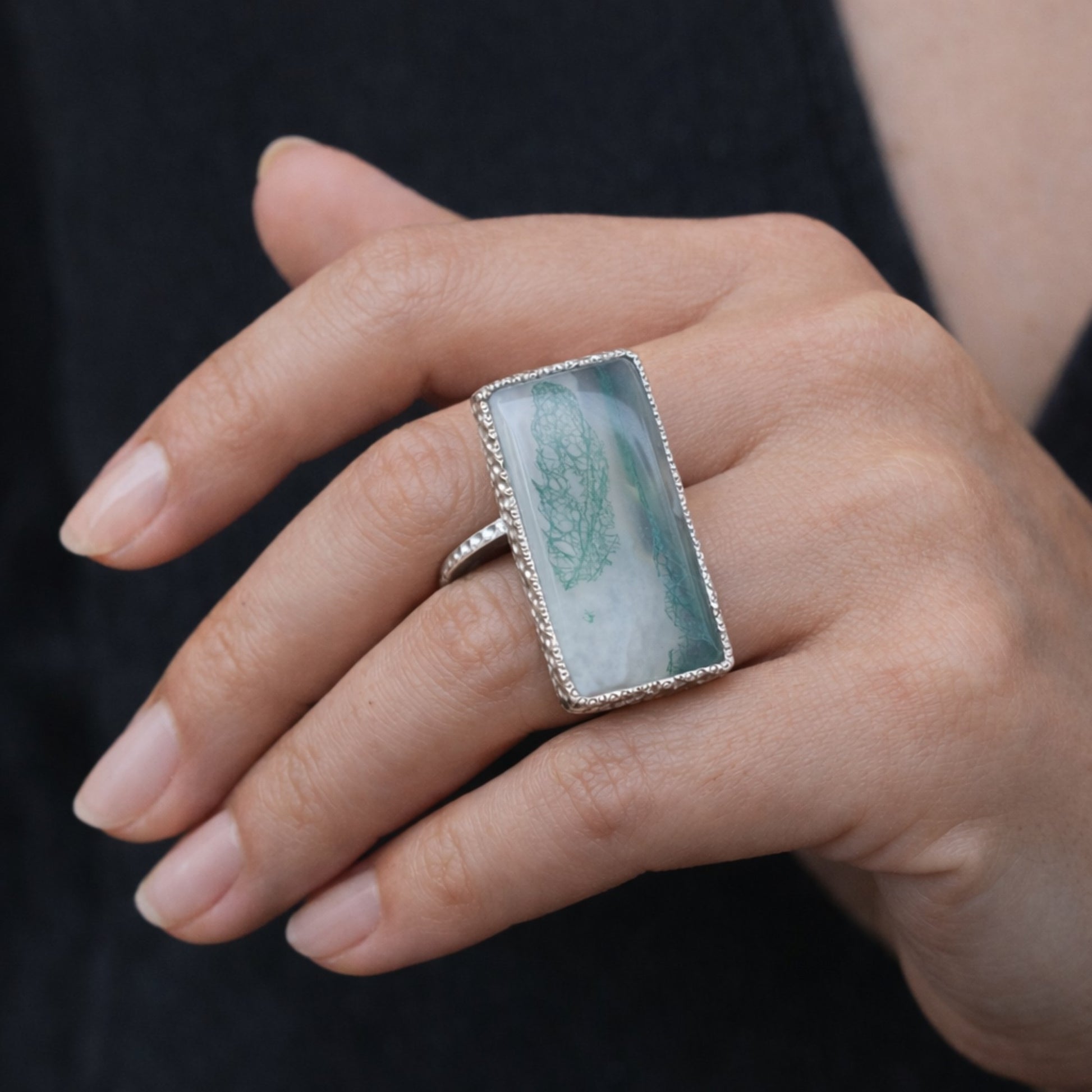 SILVER RING SHOWCASING A LARGE RECTANGULAR MOSS AGATE STONE