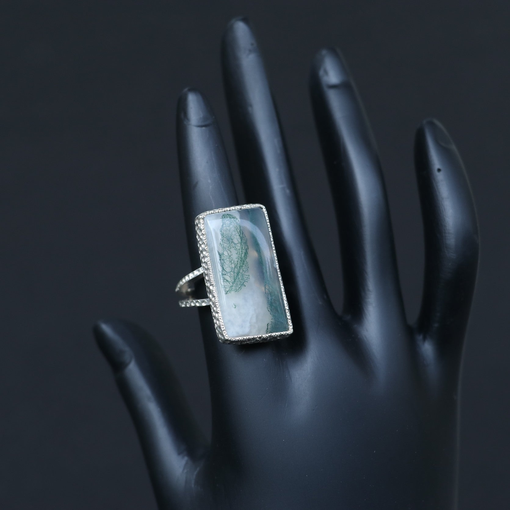 SILVER RING SHOWCASING A LARGE RECTANGULAR MOSS AGATE STONE