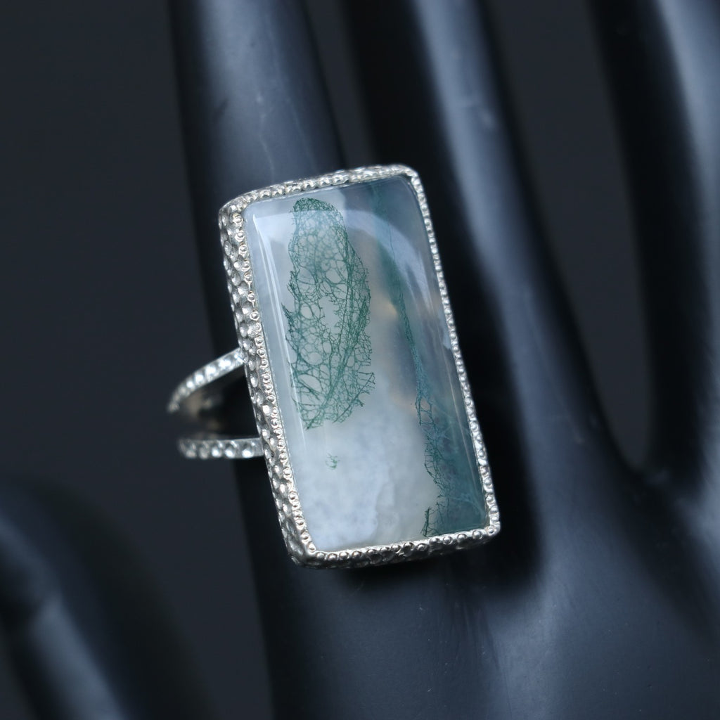 SILVER RING SHOWCASING A LARGE RECTANGULAR MOSS AGATE STONE
